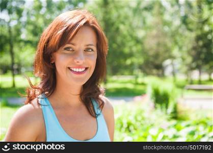 Summer girl portrait. Caucasian woman smiling happy on sunny summer or spring day outside in park. Pretty Caucasian young woman outdoors.