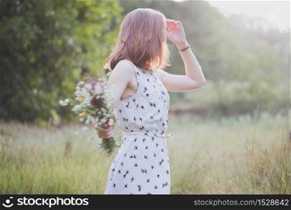 Summer - girl with a bouquet walks through the meadow. summer mood and inspiration