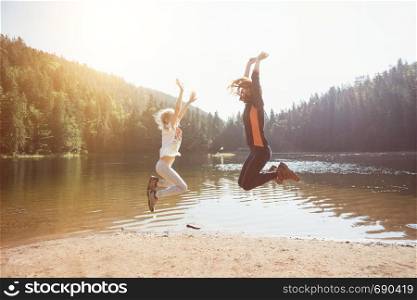 Summer - happy family on a hike. Fun happy family jumping on the shore of a mountain lake synevyr.