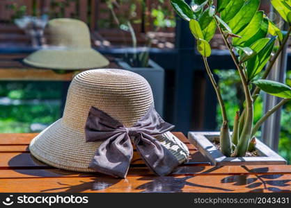 Summer hat near Zanzibar gem tree on a wooden relaxing chair for holiday background. Selective focus.