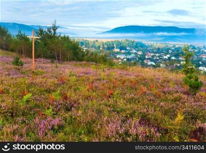 Summer heather flower hill, misty morning country view behind, and wooden crosses (Lviv Oblast, Ukraine).