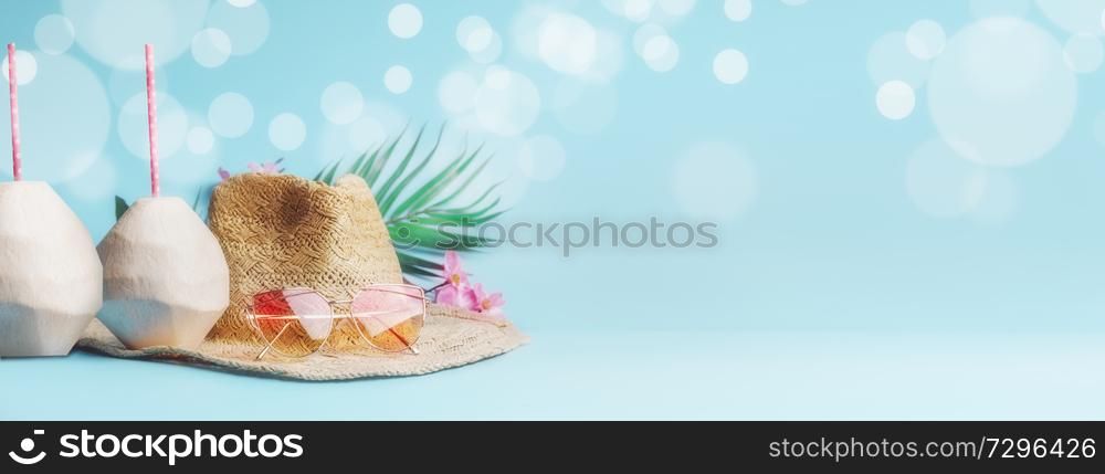 Summer holiday concept banner. Beach accessories with fresh coconut, drinking straws and tropical leaves and flowers , sunglasses and straw hat on sunny blue background with bokeh