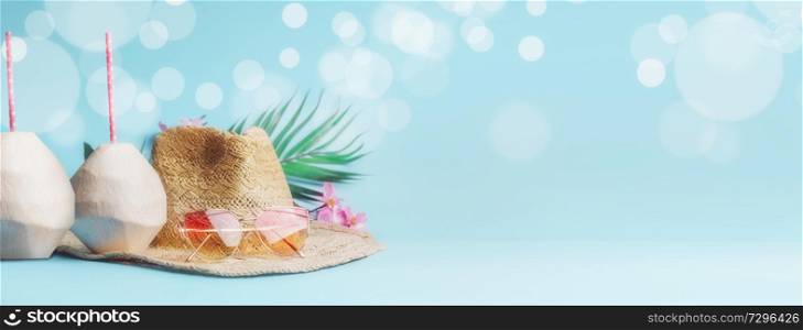 Summer holiday concept banner. Beach accessories with fresh coconut, drinking straws and tropical leaves and flowers , sunglasses and straw hat on sunny blue background with bokeh