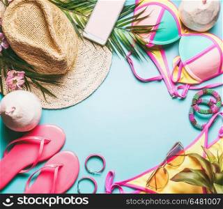 Summer holiday frame. Beach accessories : straw hat, palm leaves, sun glasses, pink flip flops , bikini and coconut cocktail on blue turquoise background, top view. Tropical vacation travel concept