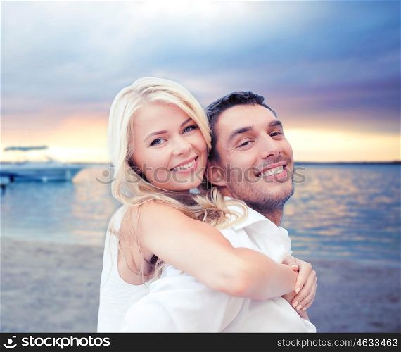 summer holiday, vacation, dating, travel and tourism concept - happy couple having fun and hugging over sunset beach background