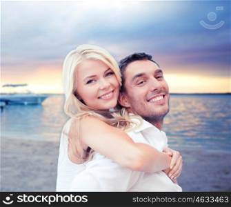 summer holiday, vacation, dating, travel and tourism concept - happy couple having fun and hugging over sunset beach background