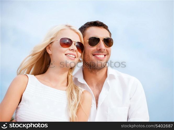summer holidays and dating concept - couple in shades at sea side