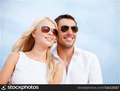 summer holidays and dating concept - couple in shades at sea side