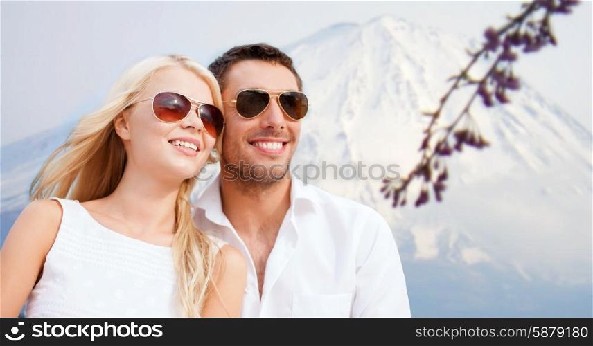 summer holidays and dating concept - couple in shades over japan mountains background. couple in shades at sea side