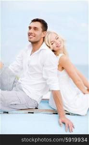 summer holidays and dating concept - couple in shades sitting at sea side. couple in shades at sea side