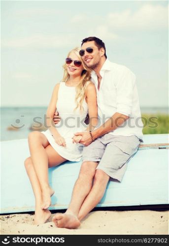 summer holidays and dating concept - couple in shades sitting at sea side