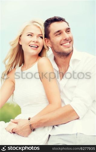 summer holidays and dating concept - couple in shades sitting at sea side