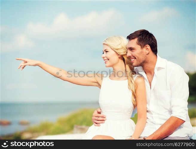 summer holidays and dating concept - couple sitting at sea side