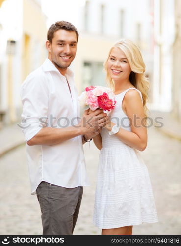 summer holidays and dating concept - couple with bouquet of flowers in the city