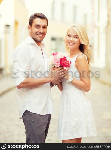 summer holidays and dating concept - couple with bouquet of flowers in the city