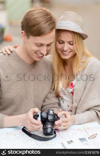 summer holidays and dating concept - couple with photo camera at cafe in the city