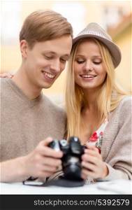 summer holidays and dating concept - couple with photo camera at cafe in the city