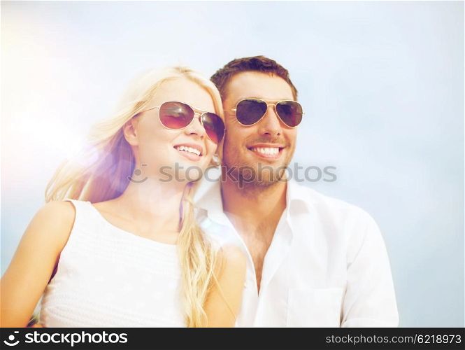 summer holidays and dating concept - happy couple in sunglasses over blue sky background. happy couple in sunglasses