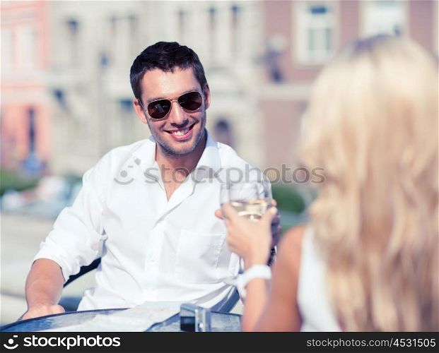 summer holidays and dating concept - man drinking wine with woman in cafe in the city. couple drinking wine in cafe