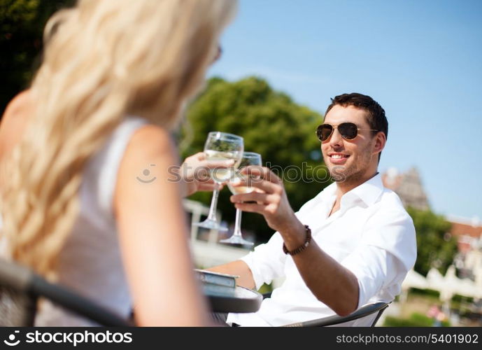 summer holidays and dating concept - man drinking wine with woman in cafe in the city