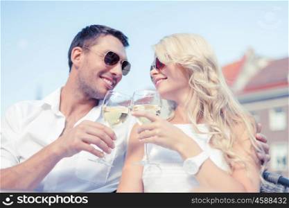 summer holidays and dating concept - smiling couple in sunglasses drinking wine in cafe. smiling couple in sunglasses drinking wine in cafe