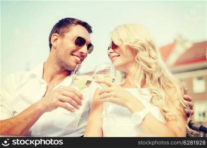 summer holidays and dating concept - smiling couple in sunglasses drinking wine in cafe