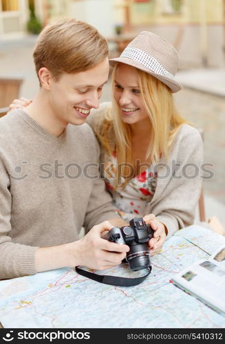 summer holidays and dating concept - smiling couple with photo camera at cafe in the city