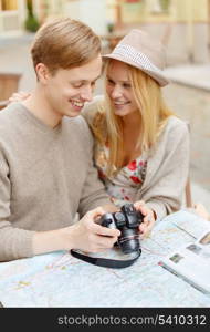 summer holidays and dating concept - smiling couple with photo camera at cafe in the city