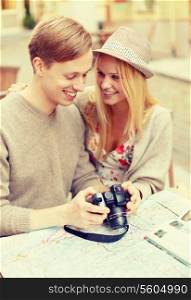 summer holidays and dating concept - smiling couple with photo camera at cafe in the city