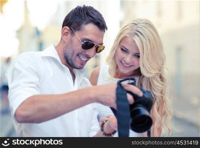 summer holidays and dating concept - smiling couple with photo camera in the city. smiling couple with photo camera