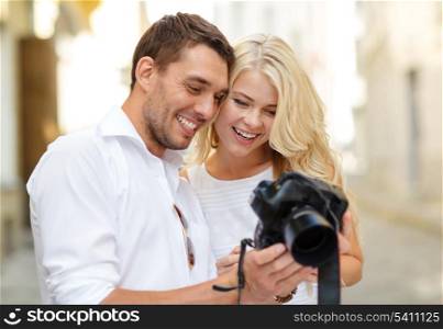 summer holidays and dating concept - smiling couple with photo camera in the city