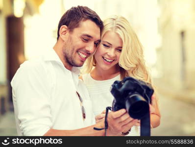 summer holidays and dating concept - smiling couple with photo camera in the city