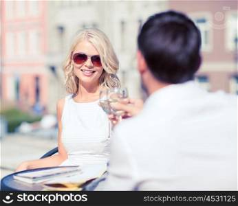 summer holidays and dating concept - woman drinking wine with man in cafe in the city. couple drinking wine in cafe