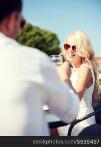 summer holidays and dating concept - woman drinking wine with man in cafe in the city