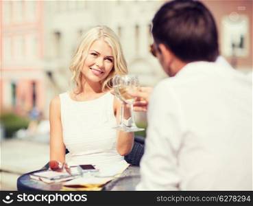 summer holidays and dating concept - woman drinking wine with man in cafe in the city