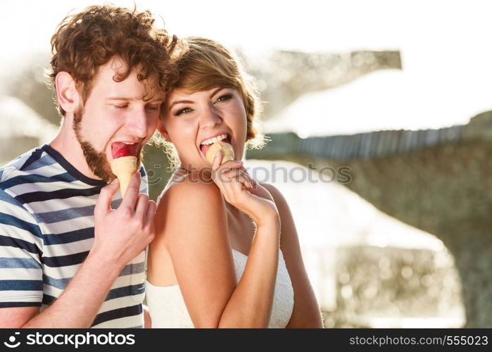 Summer holidays and happiness concept. Young couple eating ice cream outdoor city fountain in the background