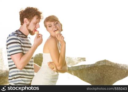 Summer holidays and happiness concept. Young couple eating ice cream outdoor city fountain in the background