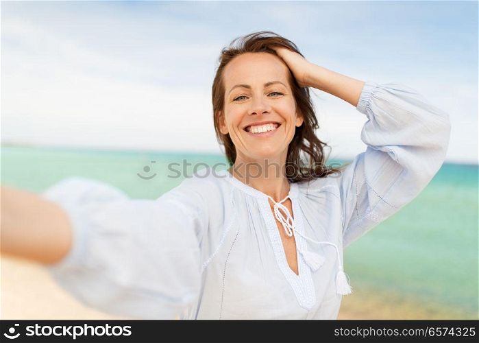 summer holidays and leisure concept - happy smiling woman taking selfie on beach. happy smiling woman taking selfie on summer beach