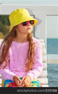 Summer holidays and leisure. Young little girl tourist in yellow cap outdoors. Child waiting for parent on seaside beach.. Portrait of girl outdoor in summer time.