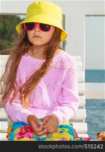 Summer holidays and leisure. Young little girl tourist in yellow cap outdoors. Child waiting for parent on seaside beach.. Portrait of girl outdoor in summer time.