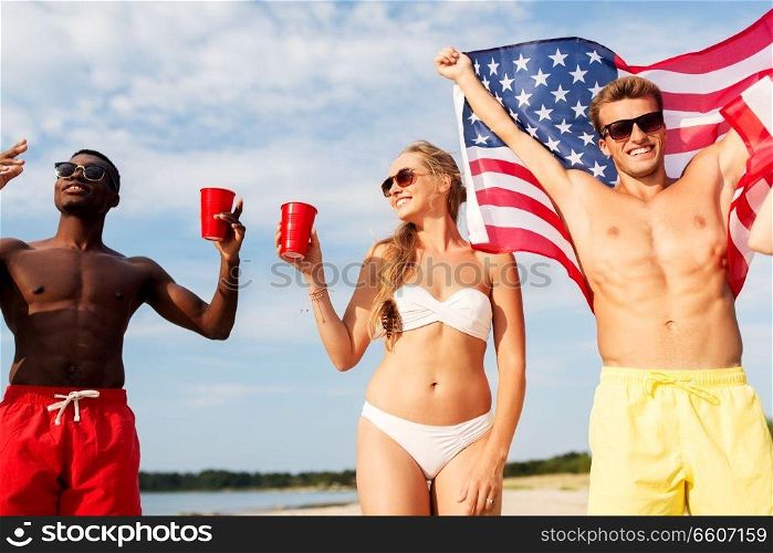 summer, holidays and people concept - group of happy friends with flag and non alcoholic drinks celebrating american independence day and party on beach. friends at american independence day beach party