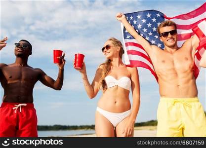 summer, holidays and people concept - group of happy friends with flag and non alcoholic drinks celebrating american independence day and party on beach. friends at american independence day beach party