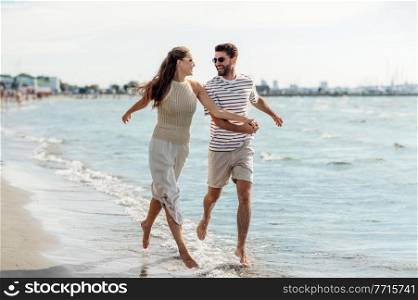 summer holidays and people concept - happy couple running along beach in tallinn, estonia. happy couple running along summer beach