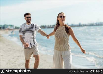 summer holidays and people concept - happy couple walking along beach in tallinn, estonia. happy couple walking along summer beach