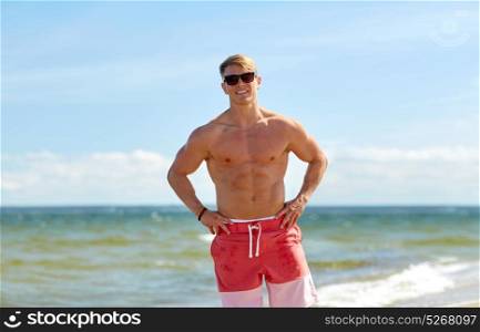 summer holidays and people concept - happy smiling young man in sunglasses on beach. smiling young man in sunglasses on summer beach