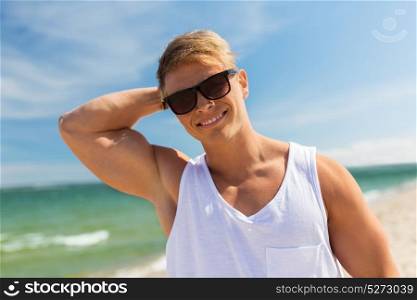 summer holidays and people concept - happy smiling young man in sunglasses on beach. smiling young man in sunglasses on summer beach