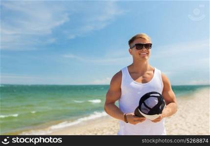 summer holidays and people concept - happy smiling young man in sunglasses with hat on beach. smiling young man in sunglasses on summer beach