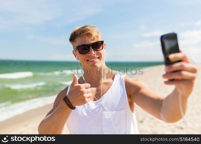 summer holidays and people concept - happy smiling young man with smartphone taking selfie on beach. man with smartphone taking selfie on summer beach