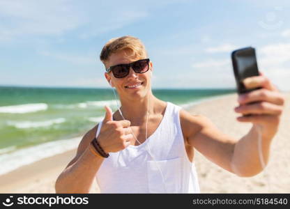 summer holidays and people concept - happy smiling young man with smartphone taking selfie on beach. man with smartphone taking selfie on summer beach