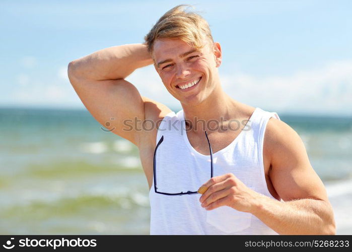 summer holidays and people concept - happy smiling young man with sunglasses on beach. smiling young man with sunglasses on summer beach